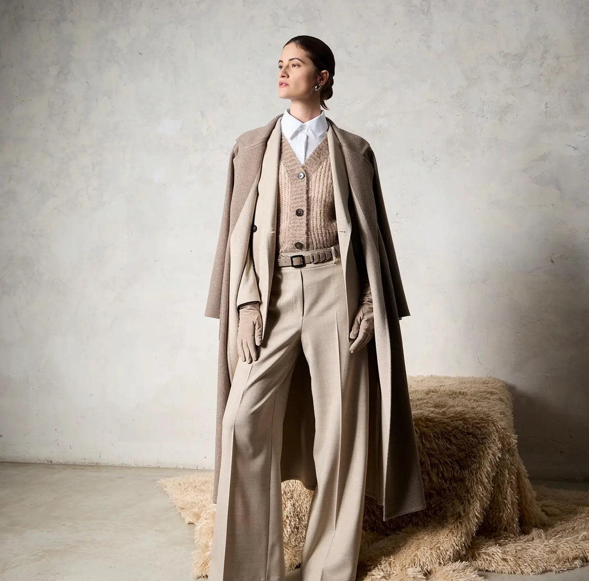 Modella con completo beige, gilet in maglia e cappotto lungo D-Exterior